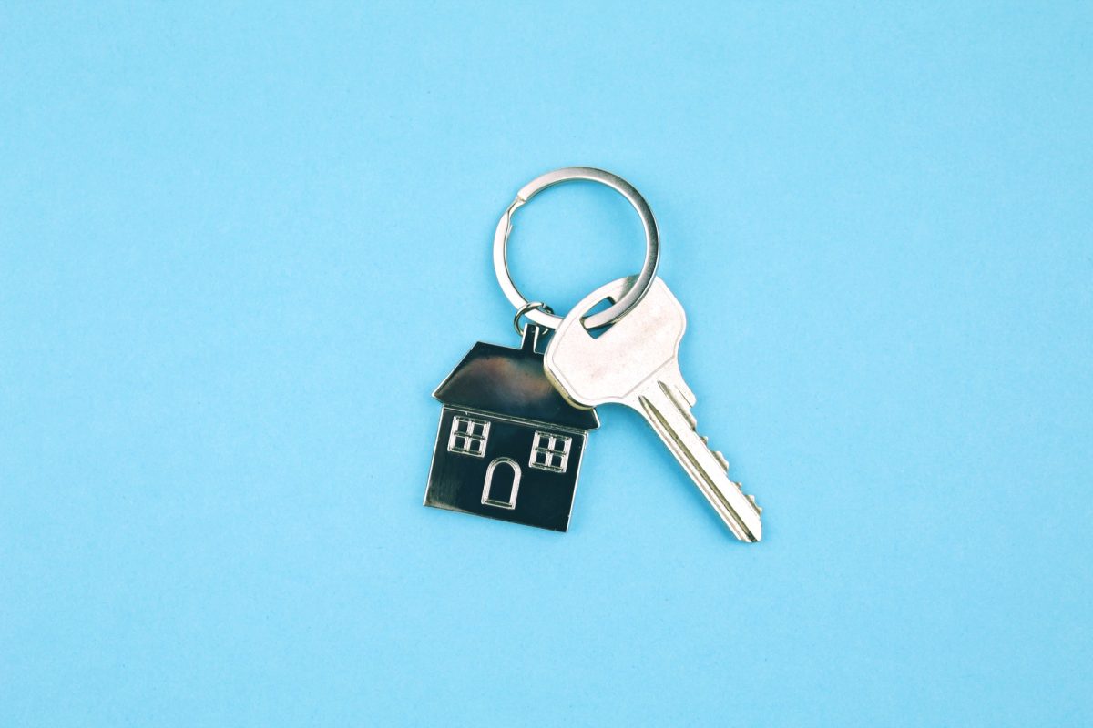key with house keychain on a blue background. Home buying concept